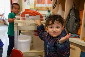 Picture of two children helping to organize things on a cart and facing the camera